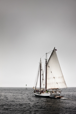 A sailboat in motion, making its way along dark waters an a dark sky.の写真素材