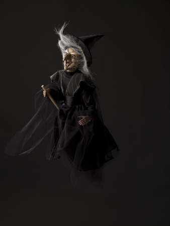 Image of a witch flying on her broom over dark background.の写真素材