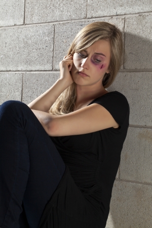 Portrait image of an abused woman sitting and leaning on the wall trying to figure out the things that are happening on herの写真素材