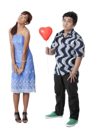 Portrait of a young couple while the man giving a heart balloon to his girlfriendの写真素材