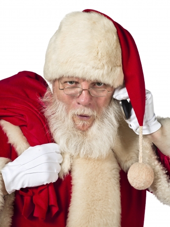A close up portrait of Santa while holding a cellular phone and a sack of gift looking straight at the cameraの写真素材