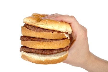 Close-up image of a hand slightly pressing the tall burger sandwich over the white backgroundの写真素材