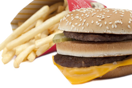 Closed up double cheeseburger and French fries over a white background