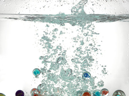 Toy marbles sinking into the waterの写真素材