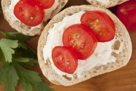 Close-up image of a slice of bread with slice tomatoes and butter on the wooden tableの写真素材