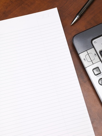 Close-up cropped shot of a blank notepad with keyboard and pen on wooden desk.の写真素材