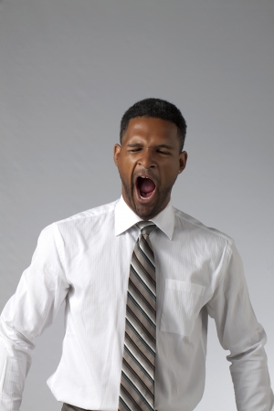 Portrait of black businesman yawning against a grey backgroundの写真素材
