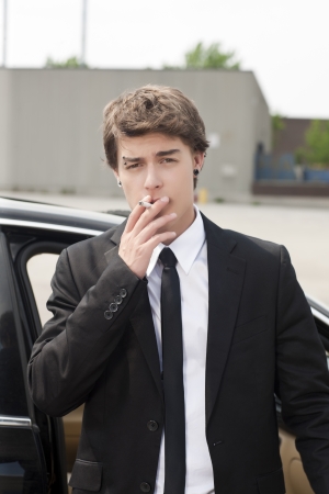 Young man in suit smoking a cigaretteの写真素材