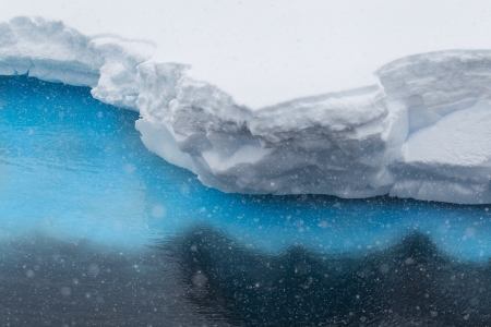 Snow captured in the air with crystal clear water of the Antarcticの写真素材