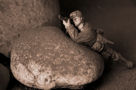 Soldier aiming his rifle as he hides himself behind some dusty rocks in the middle of the nightの写真素材
