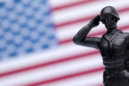 Close up image of American toy soldier with blurred American flag on backgroundの写真素材