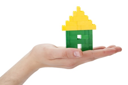 Close-up shot in the house made of lego blocks on the human's palm lifting up against the white backgroundの写真素材