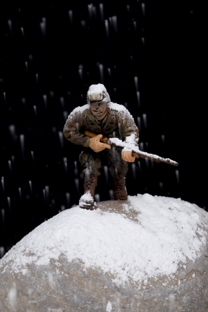 Close-up image of a brave soldier miniature fighting on the rocks under the snow rainの写真素材