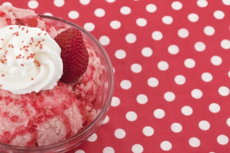 Cropped image of a strawberry ice cream with toppings on the bowl on a pink tableの写真素材