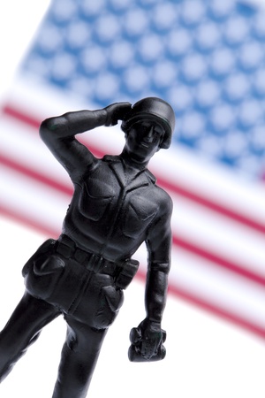 US military soldier standing at attention and saluting on a USA flag backgroundの写真素材