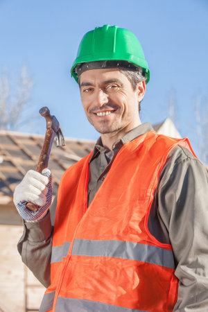 An orange vested laborer holding hammerの写真素材