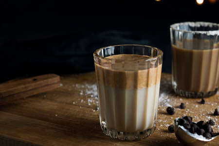 A dalgona coffee on wooden boards with bokeh background and props in backgroundの写真素材