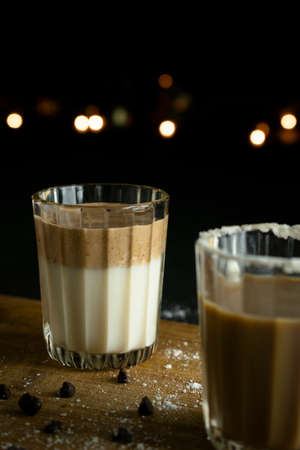 A dalgona coffee on wooden boards with bokeh background and props in backgroundの写真素材