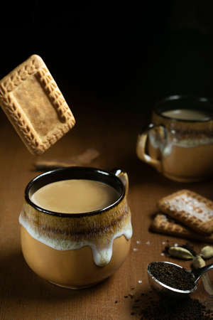 A brown cup of tea with props and dark bcakgroundの写真素材