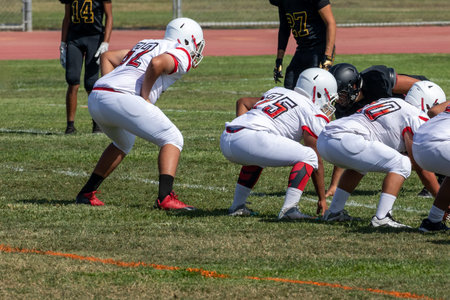 Football players on the line waiting for the snap of the football - American football