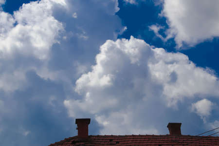Old roof and chimney and cloudy blue skyの写真素材