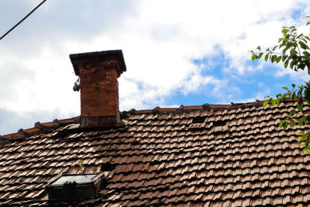 Old roof and chimney and cloudy blue skyの写真素材
