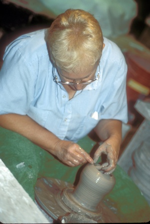Female potter uses her fingers and spins wet clay into a vase on the potterのeditorial素材