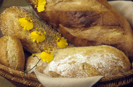 Basket of freshly baked loaves of bakery bread, decorated with yellow orchids.