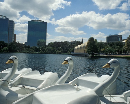 Swan boats wait at dock on Lake Eola, Orlando, Florida. Band shell and skyline in background.のeditorial素材
