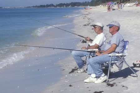 Two retirees fishing on the beach, sitting in lawn chairs at the waterのeditorial素材