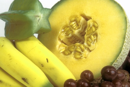 Group of healthy fruit including cut cantalope, bananas, grapes and cut starfruit の写真素材