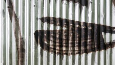 Corrugated iron sprayed with brown color. Detail of graffiti on city fence.の写真素材