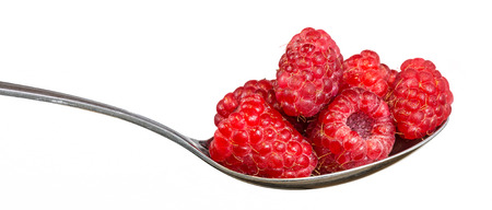 Red raspberries on a spoon. Fresh raspberries full of vitamins on glossy stainless steel spoon. Isolated on a white background.の写真素材