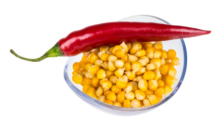 Bowl with corn and hot pepper. Yellow corn and red pepper in glass bowl isolated on white background.の写真素材