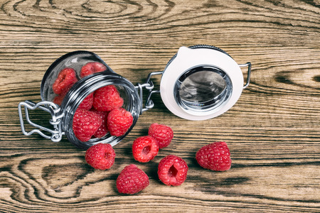Decorative detail of spilled raspberries on a wooden background. Delicious juicy refreshment on garden table.の写真素材