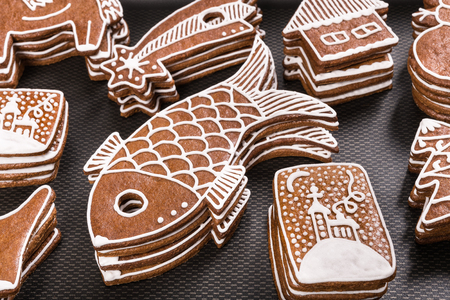 Close-up of hand-decorated traditional Christmas gingerbreads. Piles of differently shaped pastries on a black background. Cute fish, church and Bethlehem star.の写真素材