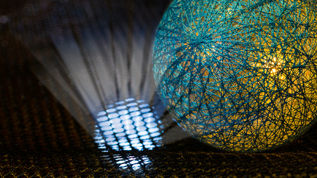 Detail of a sphere covered by net from fibers and mystery light rays in black space. Abstract background. Idea of danger, nuclear weapons, radiation, technology or sci-fi.の写真素材