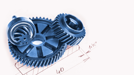 Blue metal gearwheels with a technical drawing in background. Abstract industrial background with mechanical engineering theme from cogwheels.の写真素材