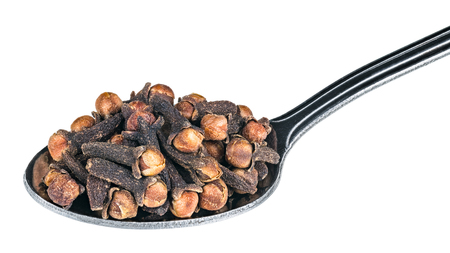 Close-up of aromatic cloves on a metal spoon. Syzygium aromaticum. Stainless spoonfull of medicinal dried spices with a distinctive scent. Isolated on white background. Full depth of field.の写真素材