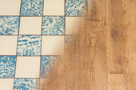 Retro ceramic tiles and modern vinyl floor. Housing renovation concept. Contrast of old worn tile facing and new wooden flooring texture. Split background. Interior reconstruction and modernization.の写真素材