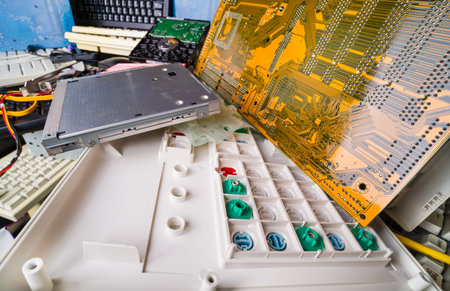 Disassembled computer hardware parts. E-waste pile detail. Keyboard with colored rubber dome...