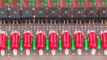 Old electronic components on retro circuit board of a galvanic isolation of data links. Obsolete red power carbon or green metallized resistors and black opto-isolators in rows. E-waste disposal. Eco.の写真素材