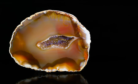 Cut agate gemstone with quartz crystals in geode on a black background. Clear and purple crystalline...