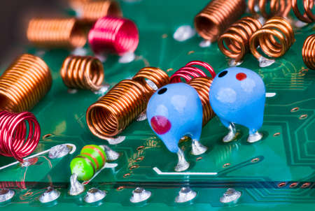 Orange and red radio-frequency coils or blue tantalum capacitors on a printed circuit board. Closeup of air core inductors soldered on green PCB. Electronic components in RF module of television card.の写真素材