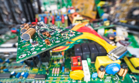 Circuit board on blur e-waste pile of discarded electric and computer devices. Air or ferrite core...