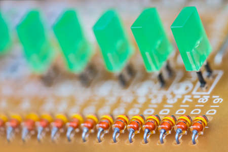 Various semiconductor or LED diodes on blur printed circuit board detail. Closeup of orange color coded or green light emitting diode rows on beige PCB. Electronics industry parts.の写真素材