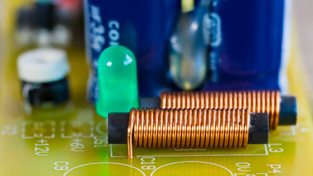 Electromagnetic coils, green LED light and electronic components on printed circuit board. Closeup of cylindric inductors with spiral copper wire or light-emitting diode on a PCB.の写真素材