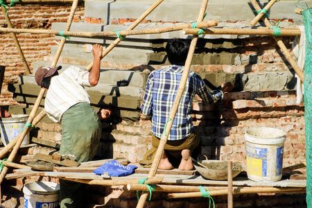 Myanmar - December 29, 2017: Burmish men are repairing local pagoda by sitting in the wooden shelvesのeditorial素材