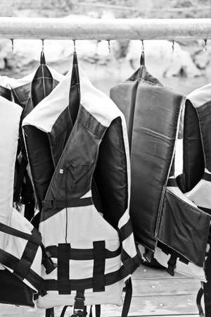 Black and white life jacket hang on metal rack for safety when in the boatの写真素材