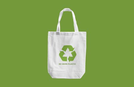 white cloth bag with Recycle sign logo and words "No more Plastic"  on green blackground.eco friendly conceptの写真素材